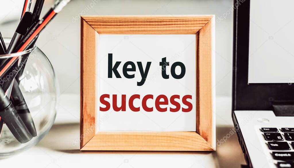 KEY TO SUCCESS text in wooden frame on office table.