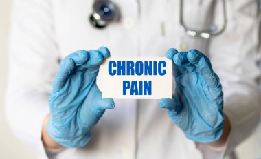 Eldivenli bir tıp çalışanının elinde CHRONIC PaIN yazılı bir kart var. Tıbbi konsept.