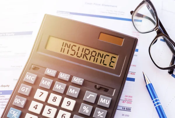 Mali belgelerde bir hesap makinesinin görüntüsünde INSURANCE kelimesi. Sigorta konsepti.