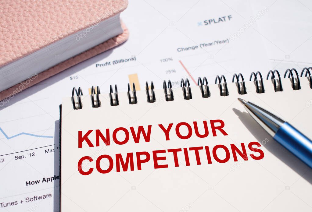 KNOW YOUR COMPETITIONS text written on notepad with pen on financial documents.