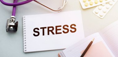 Stetoskop, haplar ve STRESS sözcüğünün olduğu defter..