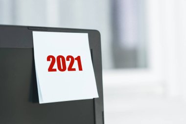 Ofisteki bilgisayar monitöründeki beyaz kağıt etiketinde 2021 nolu metni hatırlat. Yeni yıl, yeni fikir, yenilik, çözüm ve amaç.