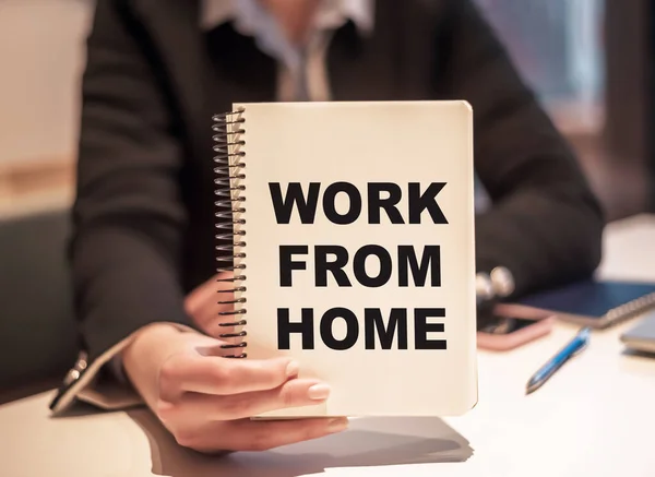 Business woman holds a notebook with the text WORK FROM HOME.