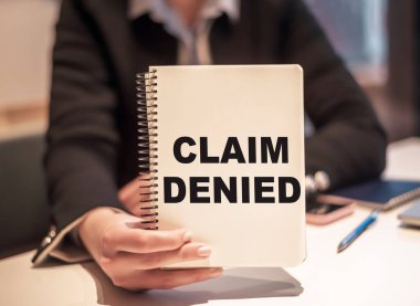 İş kadını elinde CLAIM DENIED yazılı bir defter tutuyor..
