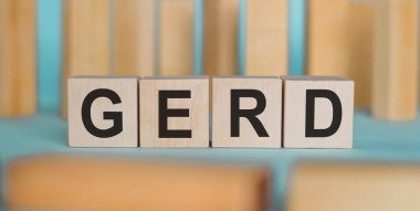 Açık mavi arkaplanda tahta bloklara yazılmış GERD kelimesi.