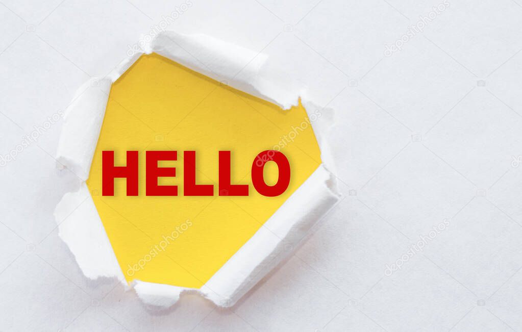 Top view of white torn paper and the text HELLO on a yellow background.