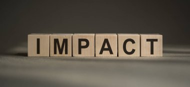 Üzerinde IMPACT yazan tahta bloklar gri bir arkaplanda..