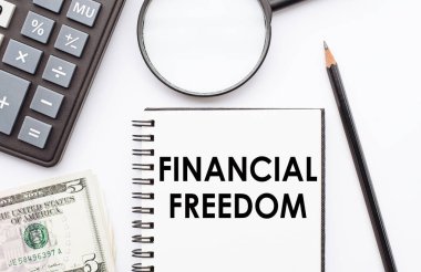 FINANCIAL FREEDOM notu ile not masasında hesap makinesi, dolar ve büyüteç ile.
