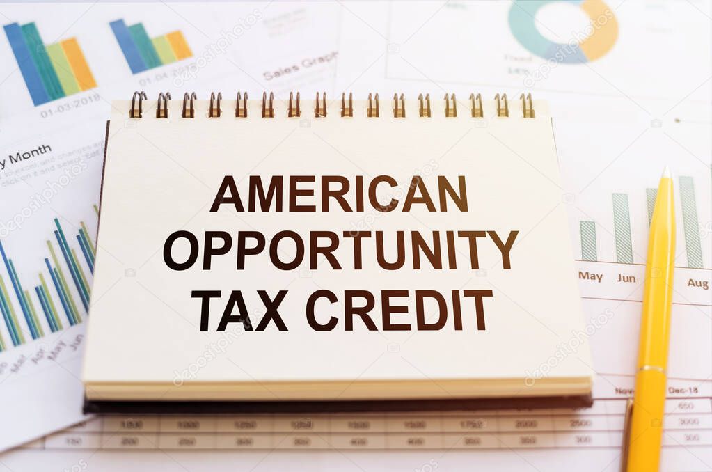 AMERICAN OPPORTUNITY TAX CREDIT - written on notepad on financial charts and graphs with yellow pen.