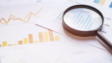 Belgelerde büyüteç olan iş konsepti. İş aşıları ve grafikleri