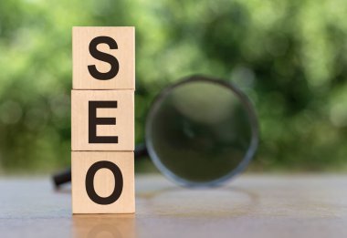 SEO Arama Motoru İyimser metin tahta küpleri ve tahta masa arkasındaki büyüteç. Fikir, Vizyon, Strateji, Analiz, Anahtar Kelime ve İçerik kavramı