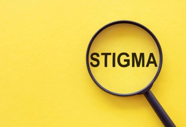 STIGMA kelimesi sarı arkaplanda bir büyüteç üzerine yazılmıştır..
