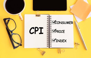 CPI - Tüketici Fiyat Endeksi kısaltması, not defterinde metin ve sarı masadaki ofis aksesuarları.