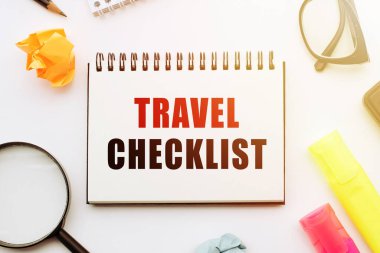 TREVEL ÇEKLİĞİ. Ofis araçlarıyla birlikte beyaz masadaki defterde metin.