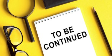 Sarı zemin üzerinde, gözlük, büyüteç ve kalemle devam edilecek metni not edin..