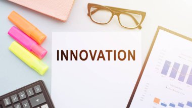 Masada renkli kalemler, gözlükler ve hesap makinesiyle yenilik metni