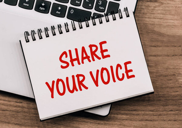 SHARE YOUR VOICE - inscription on notepad on laptop keyboard.