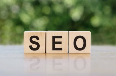 SEO - arama motoru optimizasyonu, tahta bloklara yazılmış kelime. Metin siyah harflerle yazılır ve masanın ayna yüzeyine yansıtılır. Tasarımınız için iş kavramı.