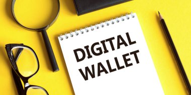 Gözlüklü, büyüteçli ve kalemli sarı zemin üzerinde Dijital Cüzdan yazan not defteri. İş konsepti.