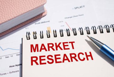 Finansal belgelerde kalemle birlikte not defterine yazılmış MARKET RESEARCH metni.