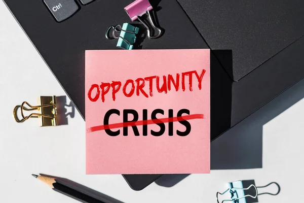 CRISIS - OPPORTUNITY note is written on a paper sticker on a laptop keyboard.