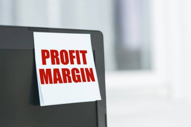 Ofisteki bilgisayar monitöründeki beyaz kağıt etiketinde PROFIT MARGIN metniyle anımsatıcı.