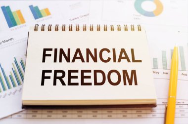 FİNANSIAL FREEDOM - Finansal tablolar üzerinde not defteri ve sarı kalemli grafikler.