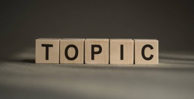 Üzerinde TOPIC yazan tahta bloklar gri arka planda..