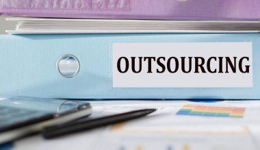 OUTSOURCING text written on folder with documents and calculator.