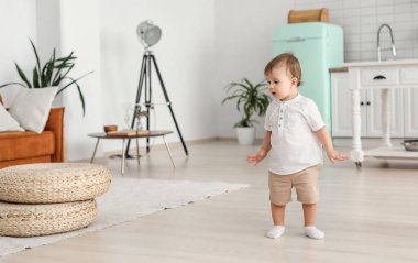 Sevimli küçük çocuk evin odasında duruyor ve nereye kaçacağını düşünüyor.