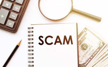 Dolar ve ofis araçlarının arka planında SCMA metni olan beyaz not defteri.