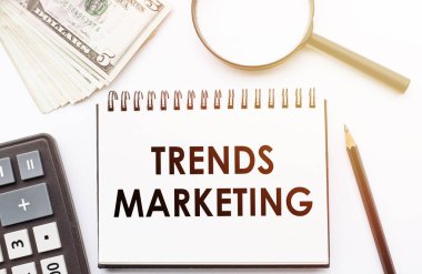 TREND MARKETING - Ofis arka planına sahip bir defter üzerine yazılmış metin.