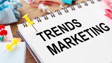 TRENDS MARKETING - Ahşap zemin üzerinde buruşuk kağıt ve kağıt iğneler ile bir not defteri üzerinde metin.