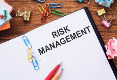 Renkli ataçlar ve buruşuk çarşaflar ile masada RISK MANAGMENT metin ile not.