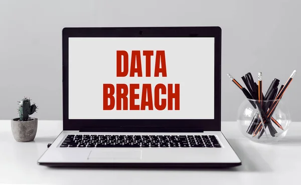 Modern ofis arka planında DATA BREACH metni olan dizüstü bilgisayar.