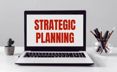 Gri arkaplanda klipsleri olan mavi bir kağıt parçası - Stratejik Planlama.