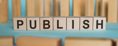 PUBLISH - açık mavi arkaplanda tahta bloklar üzerine yazılmış kelime.