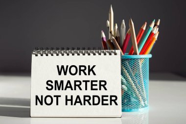 Work smarter not harder inscription on a notebook with colored pencils. Business concept