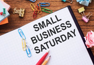 Üzerinde küçük işletme cumartesi günü renkli ataçlar ve buruşuk çarşaflar olan bir not..