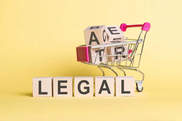 Das Wort Legal Auf Holzwürfeln Auf Gelbem Hintergrund Mit Einkaufswagen — Stockfoto