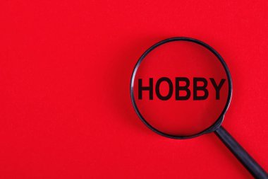 Kırmızı arka planda HobBY yazısıyla büyüteç.