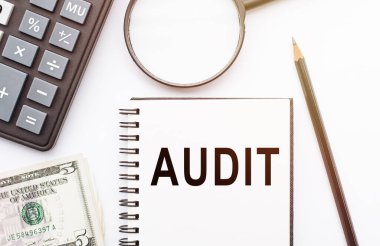 Masasında AUDIT notu, hesap makinesi, dolar ve büyüteç olan not defteri..