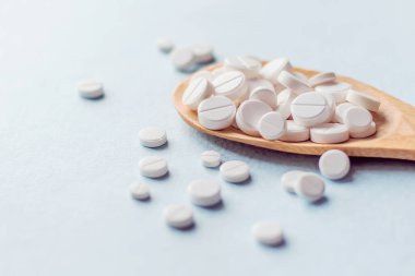 Tahta kaşıkta ilaç tabletleri beyaz arka planda izole edilir.