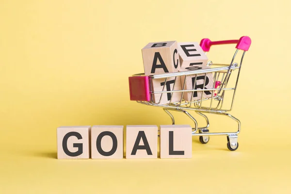 Das Wort Goal Auf Holzwürfeln Auf Gelbem Hintergrund Mit Einkaufswagen — Stockfoto