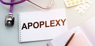 Stetoskop, haplar ve not defteri. Tıp masasında APOPLEXY kelimesi var..