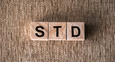 STD - Cinsel yolla bulaşan hastalıklar, kahverengi arka planda tahta bloklara yazılmış kelimeler.