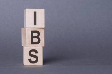 IBS - Alıngan Bağırsak Sendromu, tahta bloklara yazılmış yazı, gri arkaplan.