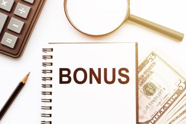 Dolar ve ofis araçlarının arka planında BONUS metni olan beyaz not defteri.