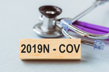 2019N ile steteskop - Ahşap küp üzerinde COV sözcükleri.