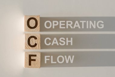 OCF sözcüğüyle tahta küpler - Cash Flow Operasyonu, gri arka planda düşen bir gölge.